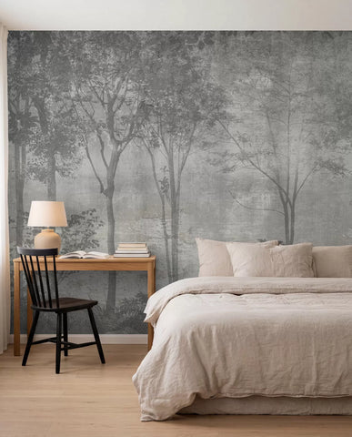 Grey misty forest wall mural on a stone texture behind a bed with linen bedding and a wooden desk