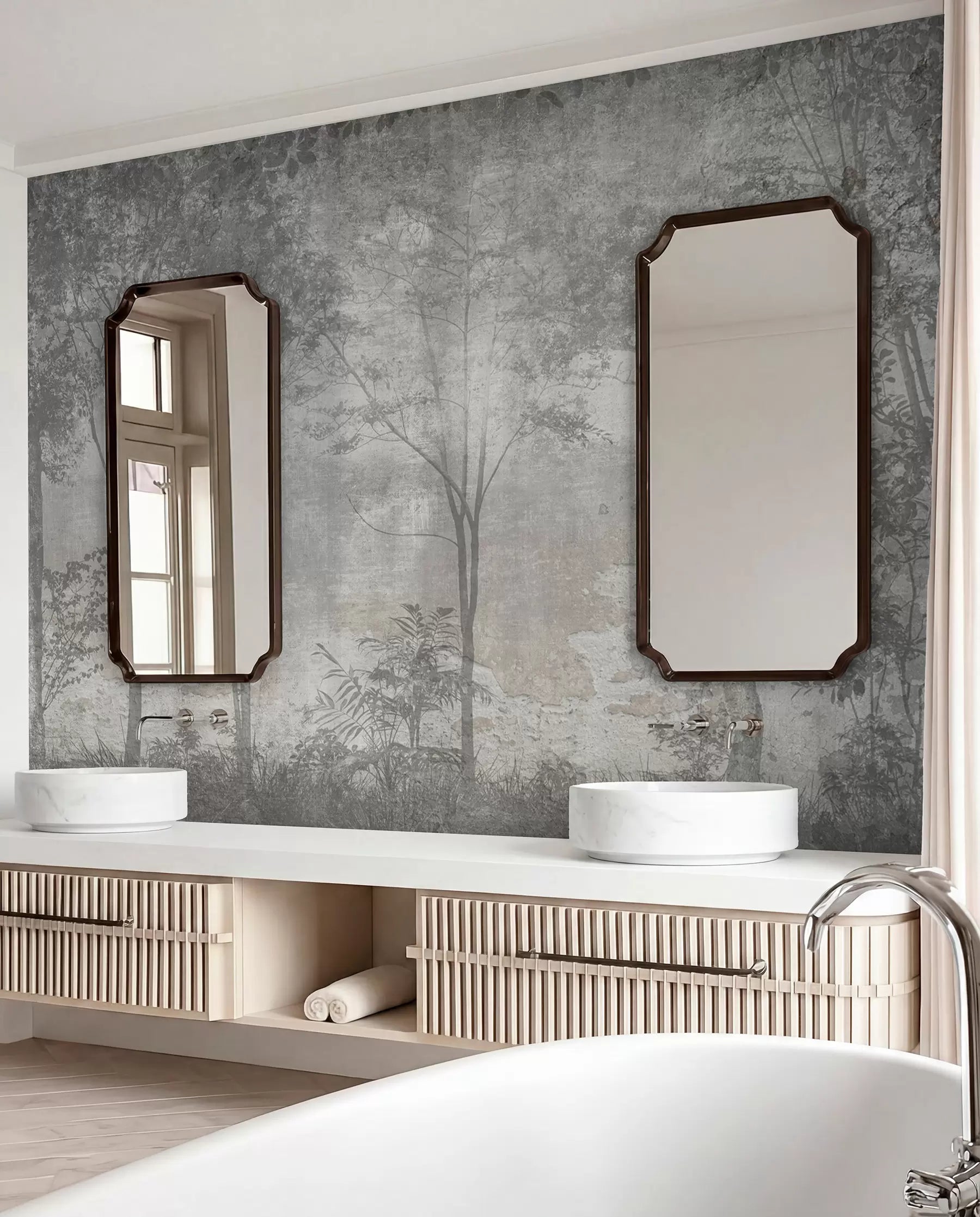 Grey forest on stone wall mural in a bathroom behind a double vanity with two mirrors and a freestanding tub