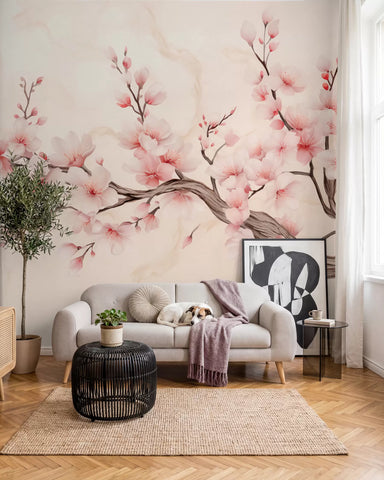 Pink cherry blossom wall mural behind a light grey sofa in a living room with a jute rug and potted olive tree