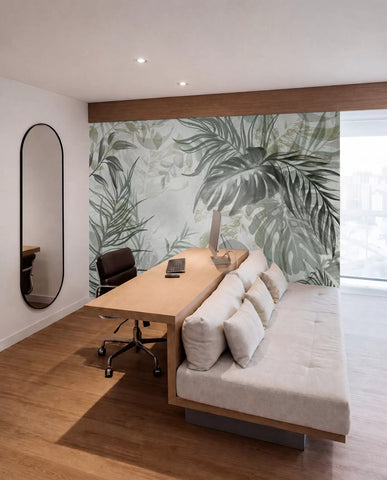Green and grey tropical leaf mural in a room with a sofa and wooden desk