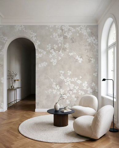 Delicate white twigs and flowers on warm taupe wall mural in a room with an arched doorway and armchair