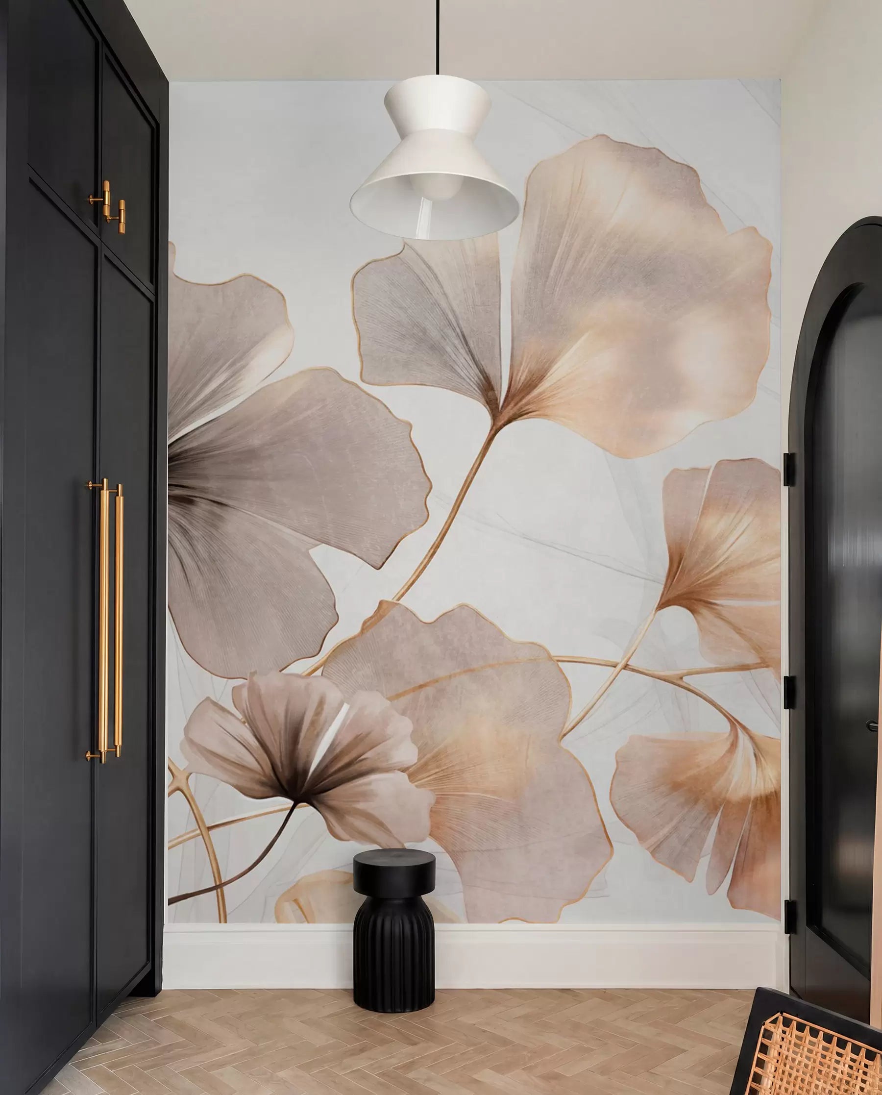 Oversized watercolor ginkgo leaves wall mural in beige and blush in a hallway with black doors