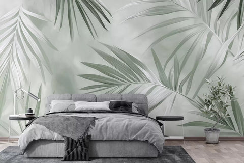 Misty grey-green palm leaves wall mural behind a bed with grey bedding