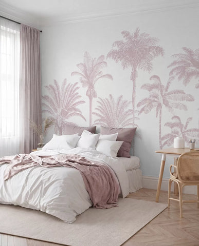 Blush pink palm tree oasis wall mural behind a bed with pink bedding