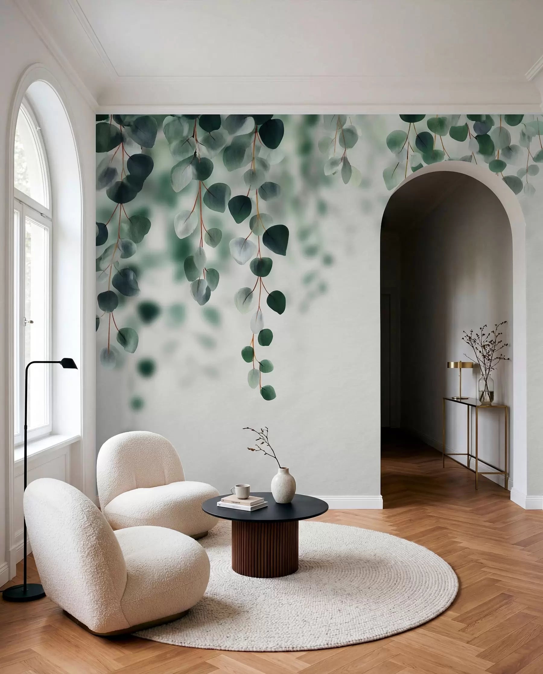 Falling eucalyptus leaves wall mural on white in a room with an arched doorway and boucle armchairs