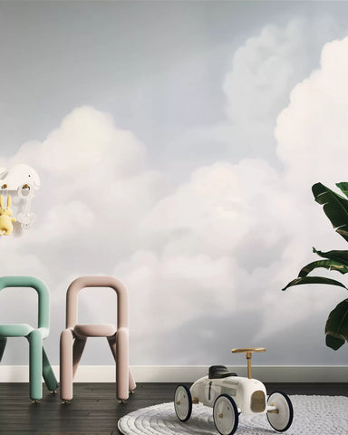 Soft blue sky and clouds mural in a kids' room with small chairs and a toy car