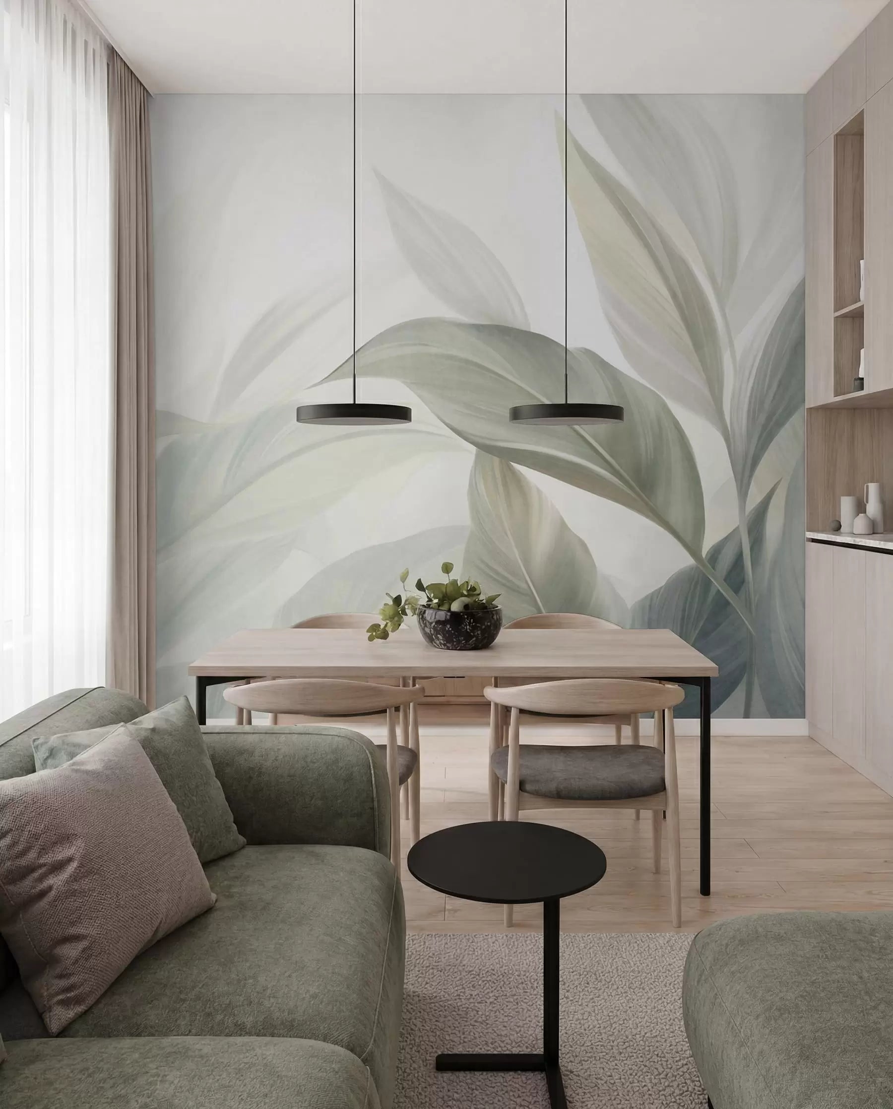 Soft sage green tropical leaves wall mural in an open-plan dining area with a green sofa