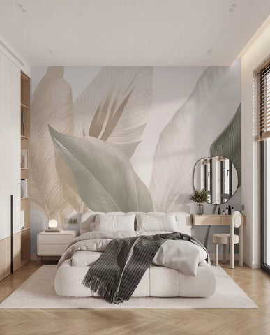 Overlapping large leaf forms wall mural in beige and sage behind a white bed with a grey throw